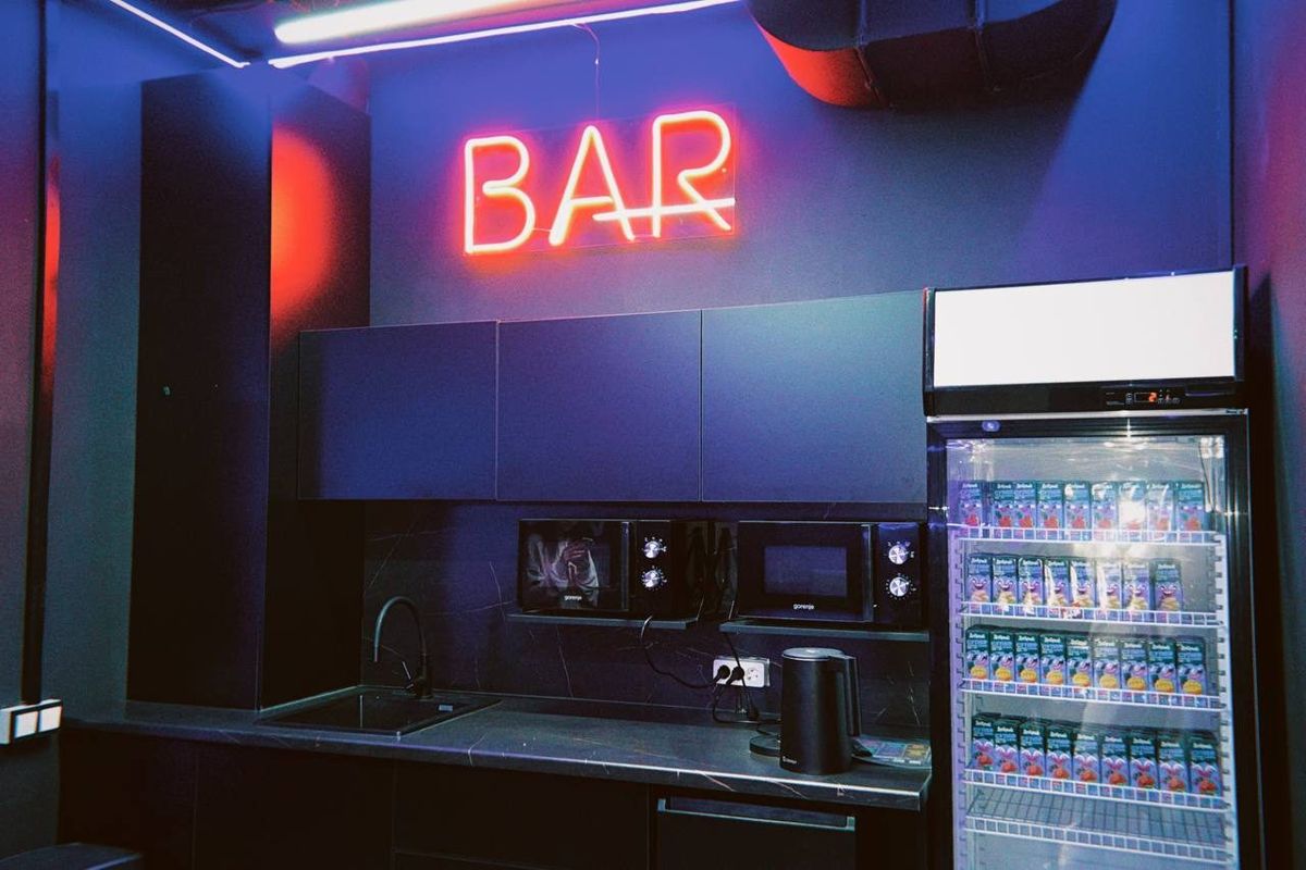 Бар с неоновой вывеской BAR и холодильником с напитками